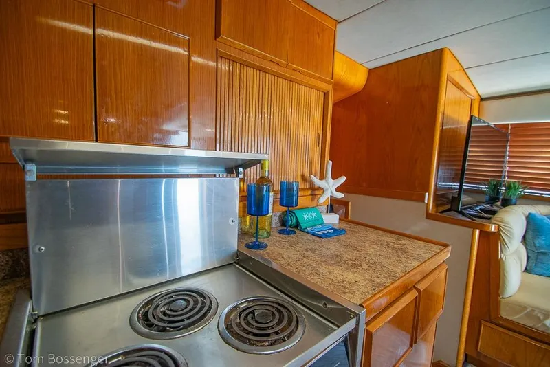 Slide: The Image of 1989 Bertram 50 Convertible yacht interior with stove and wooden cabinetry. - 19