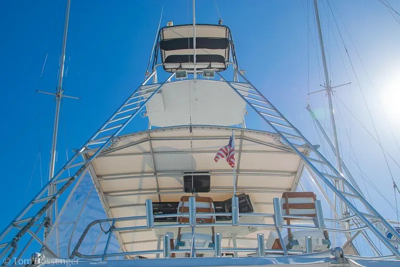 Slide: The Image of 1989 Bertram 50 Convertible yacht with American flag, viewed from below against clear blue sky. - 37