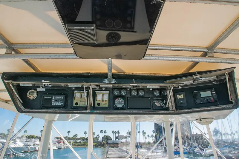 Slide: The Image of 1989 Bertram 50 Convertible yacht dashboard with gauges and controls, marina view in background. - 43