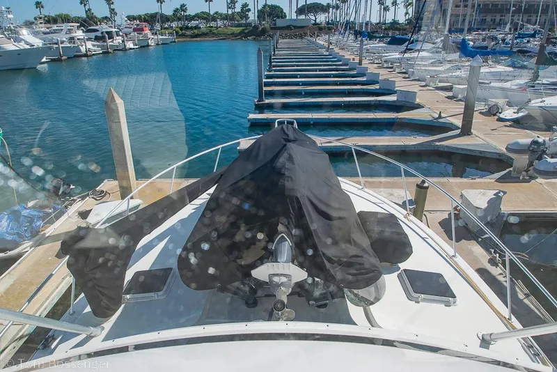 Slide: The Image of 1989 Bertram 50 Convertible yacht docked in a marina, surrounded by clear blue water. - 50