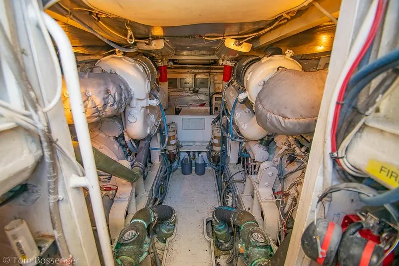 Slide: The Image of Engine room of a 1989 Bertram 50 Convertible yacht, showcasing dual engines and mechanical components. - 56