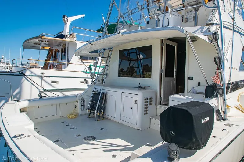 Slide: The Image of 1989 Bertram 50 Convertible yacht docked, featuring spacious deck and fishing equipment. - 7