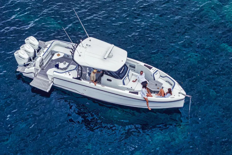 Slide: The Image of 2026 Wellcraft 38 T-Top boat cruising on clear blue water with passengers relaxing. - 2