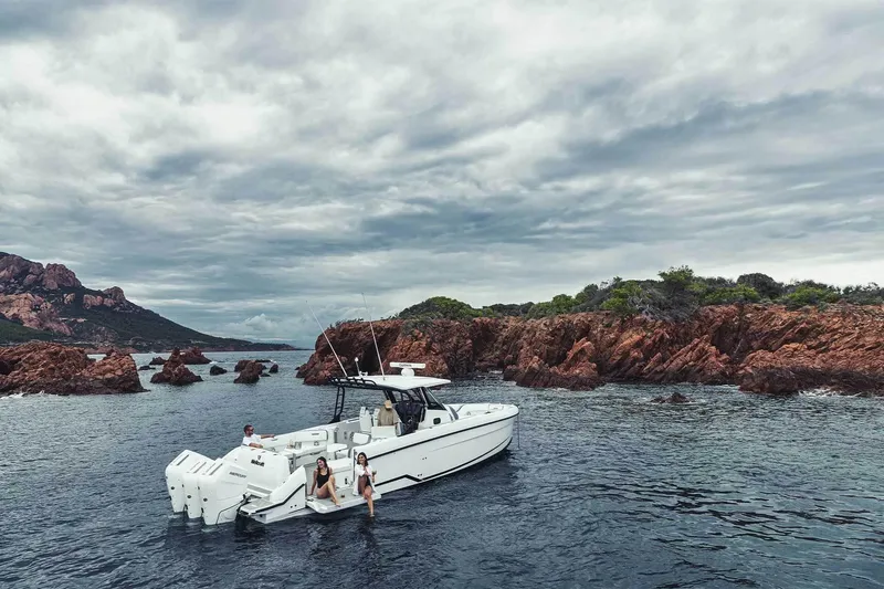 Slide: The Image of 2026 Wellcraft 38 T-Top boat cruising near rocky coastline under cloudy skies. - 3