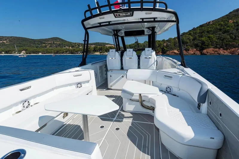 Slide: The Image of 2026 Wellcraft 38 T-Top boat interior with white seating, tables, and ocean view. - 5