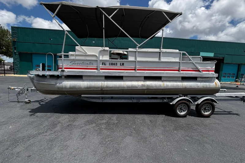 The Image of 2001 Godfrey Sweetwater 20 pontoon boat on trailer, parked outdoors under cloudy sky. - 1