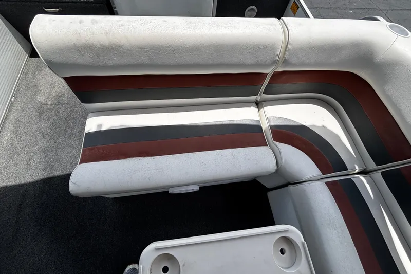 Slide: The Image of 2001 Godfrey Sweetwater 20 boat interior with striped seating and carpeted floor. - 7
