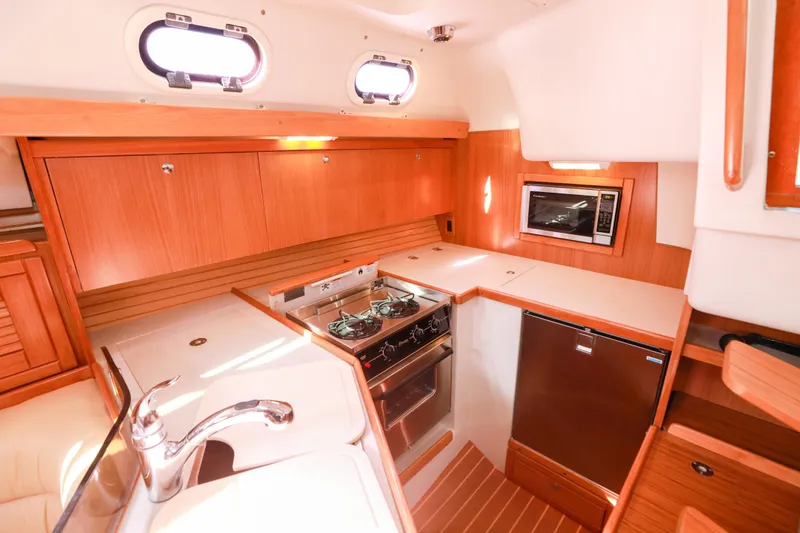 Slide: The Image of 2010 Catalina 375 yacht kitchen with stove, microwave, and wooden cabinetry. - 30