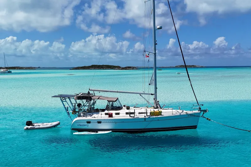 The Image of 2004 Hunter 41 Aft Cockpit sailboat anchored in clear turquoise waters under a blue sky. - 0