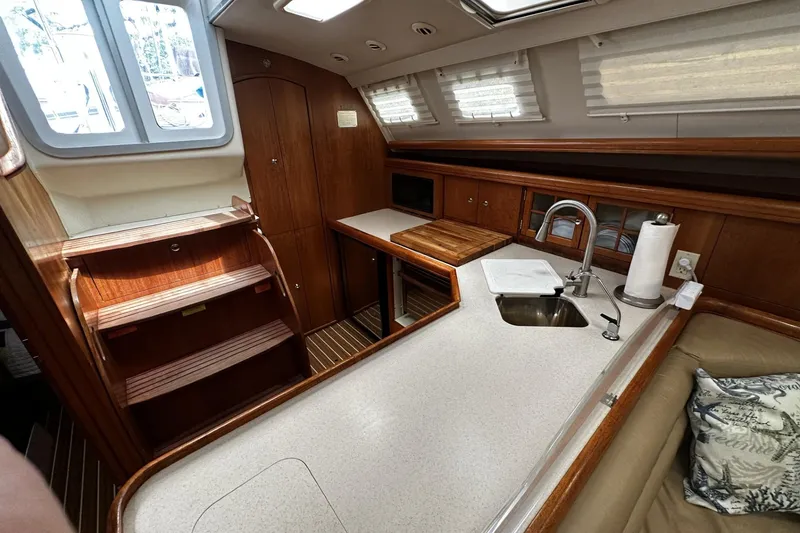 Slide: The Image of Interior of 2004 Hunter 41 Aft Cockpit yacht with wooden cabinetry and compact kitchen area. - 16