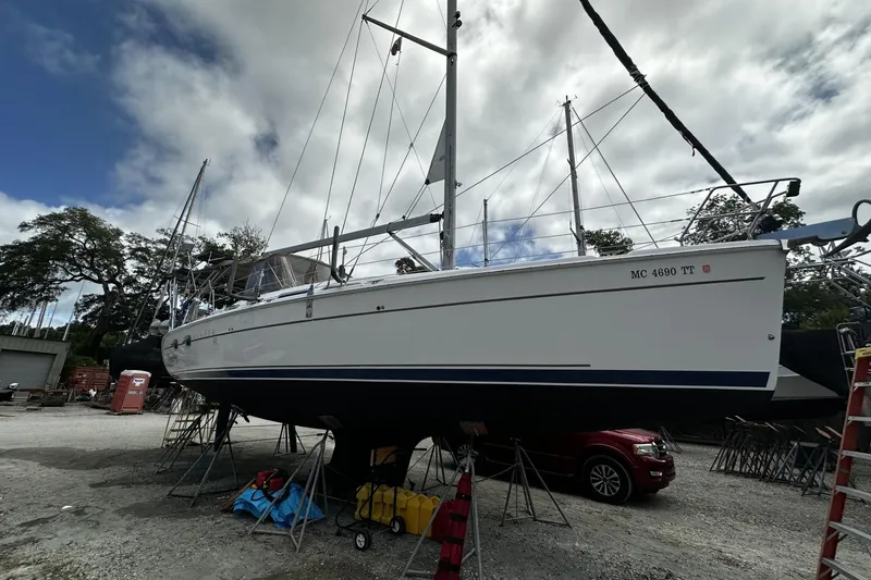 Slide: The Image of 2004 Hunter 41 Aft Cockpit sailboat on stands, under cloudy sky, in a boatyard. - 2