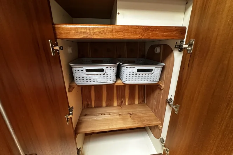 Slide: The Image of Wooden cabinet interior with shelves and storage baskets on a 2004 Hunter 41 Aft Cockpit. - 32