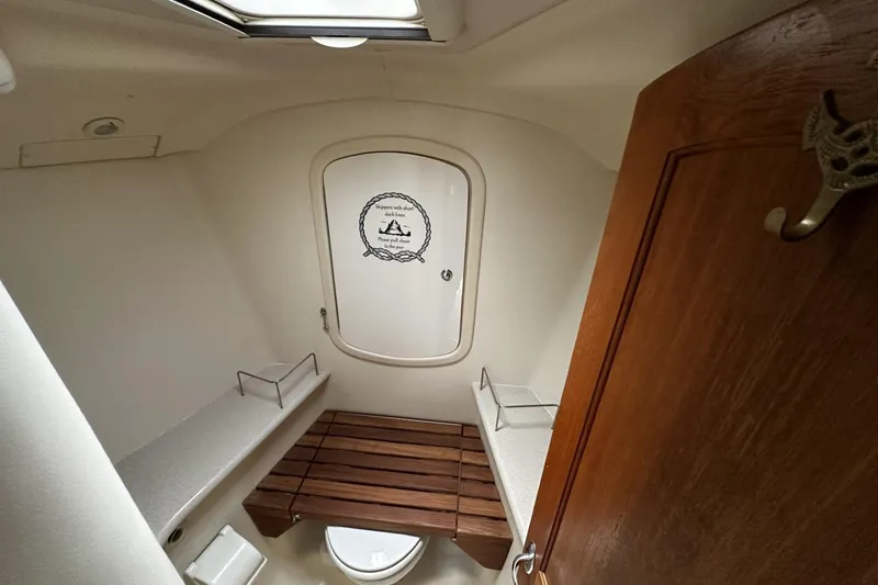 Slide: The Image of 2004 Hunter 41 Aft Cockpit bathroom with wooden seat and nautical decor. - 33