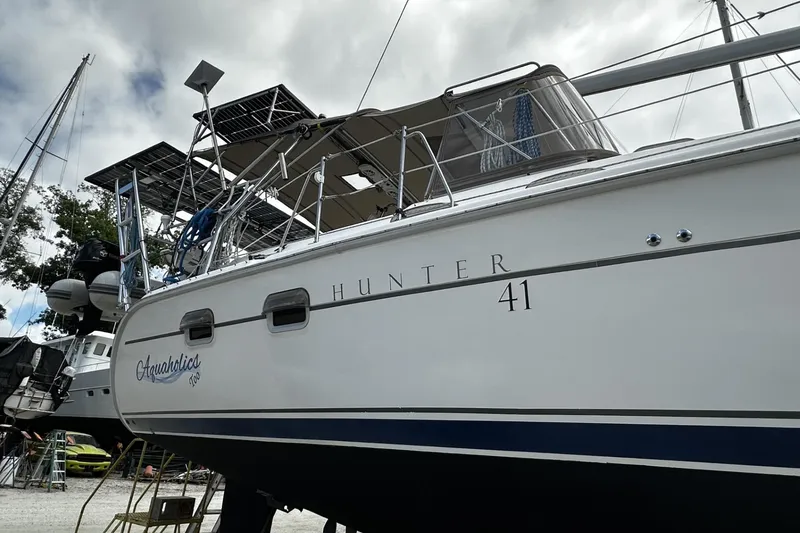 Slide: The Image of 2004 Hunter 41 Aft Cockpit sailboat with solar panels, docked under cloudy skies. - 56
