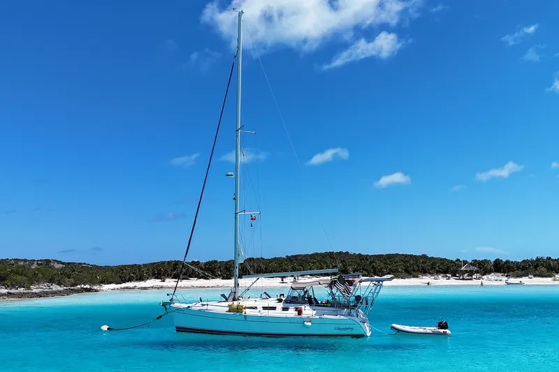 Slide: The Image of Sailboat "Hunter 41 Aft Cockpit" 2004 anchored in turquoise waters near a sandy beach. - 62