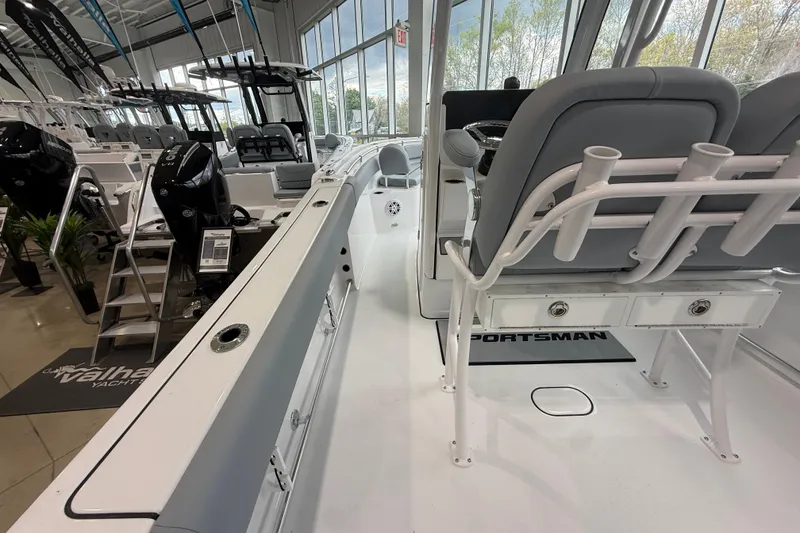 Slide: The Image of 2026 Sportsman Open 232 Center Console boat interior in showroom, featuring seating and rod holders. - 16