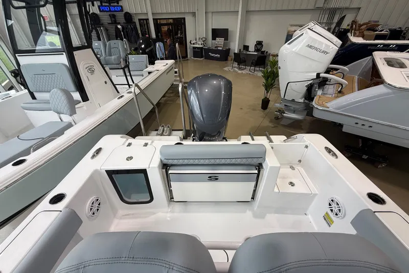 Slide: The Image of 2026 Sportsman Open 232 Center Console boat interior with seating and motor in showroom. - 19
