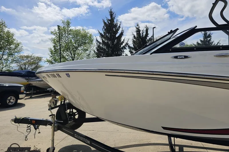 Slide: The Image of 2020 Glastron GTS 225 boat on trailer under a clear blue sky. - 26