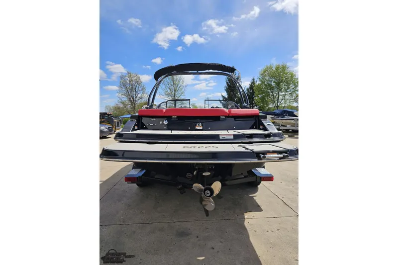 Slide: The Image of 2020 Glastron GTS 225 boat, rear view, parked outdoors under a blue sky. - 35