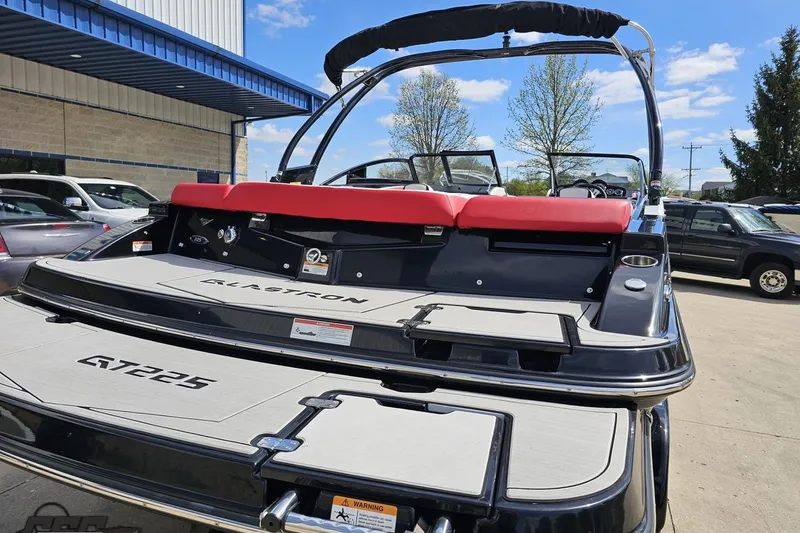 Slide: The Image of 2020 Glastron GTS 225 boat with red seating, parked outdoors under blue sky. - 36