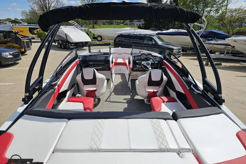 Slide: The Image of 2020 Glastron GTS 225 boat interior with red and white seating, parked outdoors. - 43