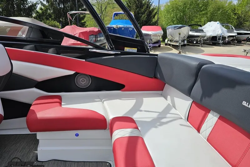 Slide: The Image of 2020 Glastron GTS 225 boat interior with red and white seating, docked outdoors. - 50