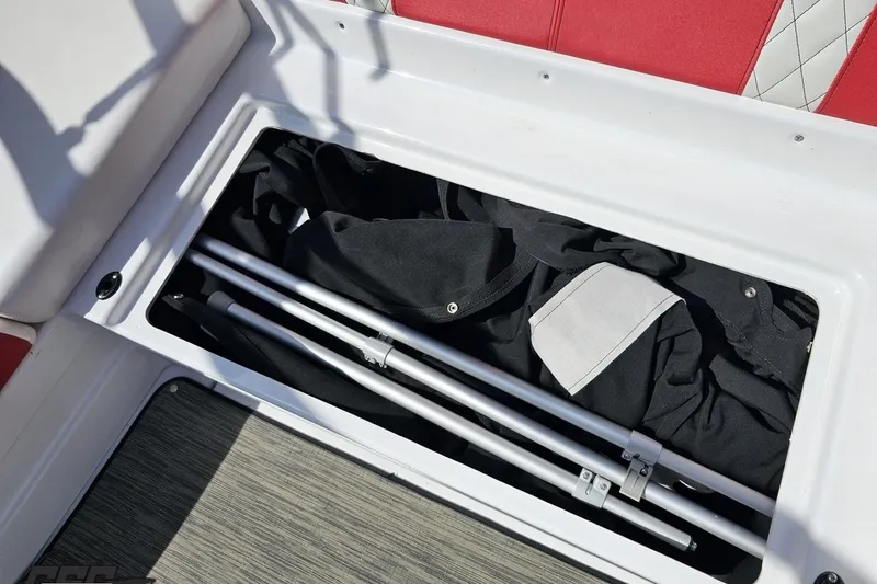 Slide: The Image of Storage compartment in a 2020 Glastron GTS 225 boat with folded fabric and poles. - 96