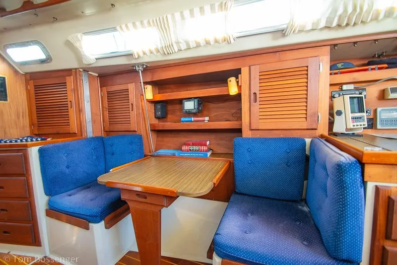 Slide: The Image of Interior of a 1987 Catalina 36 sailboat with blue cushioned seating and wooden cabinetry. - 17
