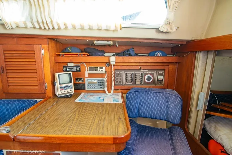 Slide: The Image of Navigation station inside a 1987 Catalina 36 sailboat with control panels and seating. - 24