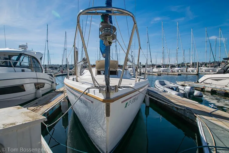 Slide: The Image of 1987 Catalina 36 sailboat docked at a marina, surrounded by other boats under a clear blue sky. - 4