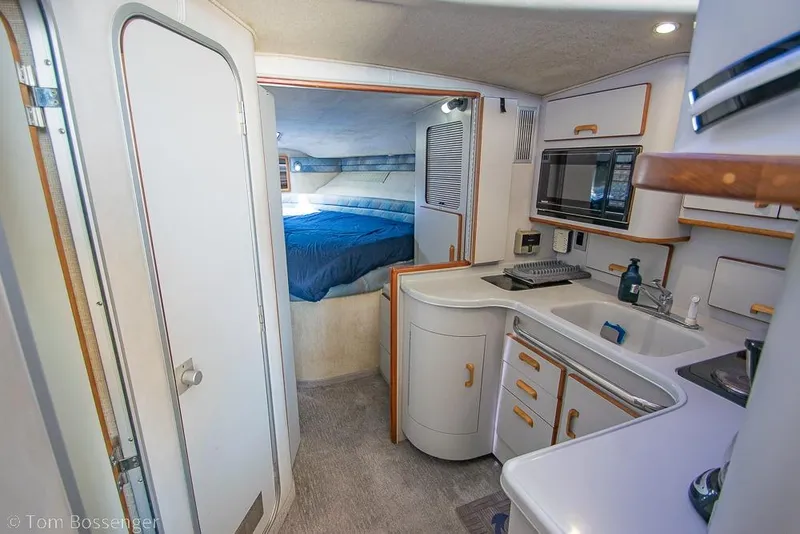 Slide: The Image of 1991 Sea Ray 370 Sedan Bridge interior with kitchenette and cozy sleeping area. - 16