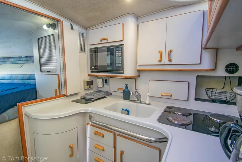 Slide: The Image of 1991 Sea Ray 370 Sedan Bridge kitchen with white cabinetry and modern appliances. - 17