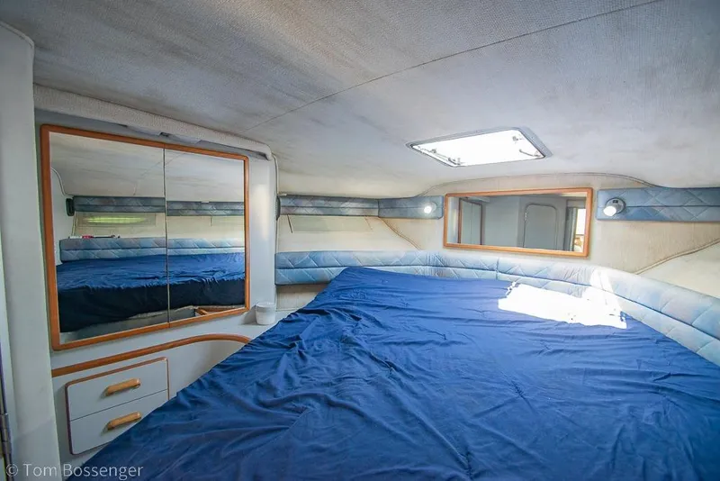 Slide: The Image of Interior cabin of 1991 Sea Ray 370 Sedan Bridge with blue bedding and mirrored storage. - 21