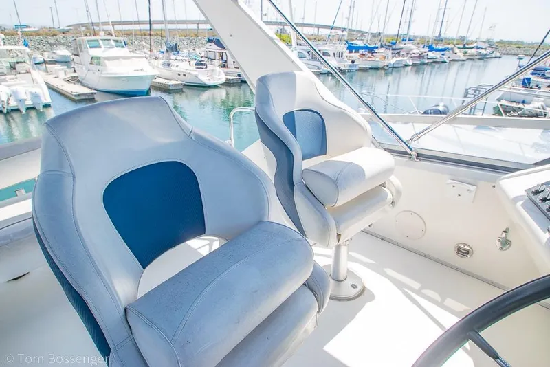 Slide: The Image of 1991 Sea Ray 370 Sedan Bridge helm with marina view, featuring comfortable captain chairs. - 31