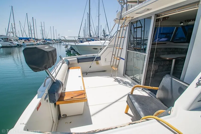 Slide: The Image of 1991 Sea Ray 370 Sedan Bridge yacht docked at marina, featuring spacious deck and seating. - 7