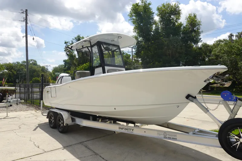 Slide: The Image of 2026 Sea Hunt Ultra 245 SE boat on trailer, parked outdoors under a cloudy sky. - 3