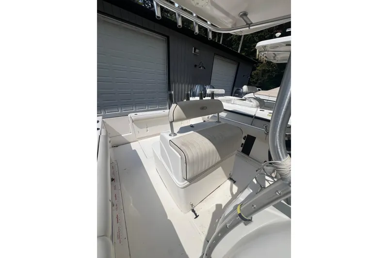 Slide: The Image of 2005 Robalo R220 Center Console boat interior with seating and storage, parked near a garage. - 2