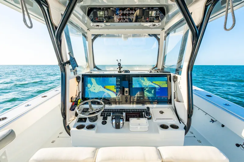 Slide: The Image of 2022 Freeman 42LR boat cockpit with dual navigation screens, steering wheel, and ocean view. - 24