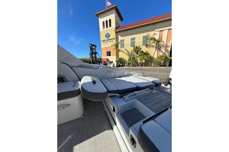 Slide: The Image of 2026 Crownline 310 XSS boat interior with seating, docked near a building under clear blue sky. - 15