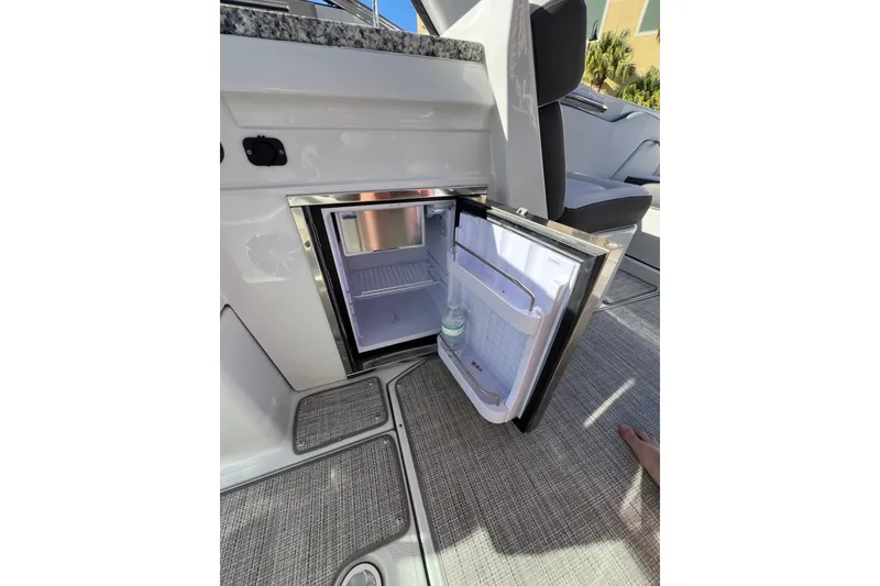 Slide: The Image of Open mini fridge on 2026 Crownline 310 XSS boat, showcasing interior storage space. - 19