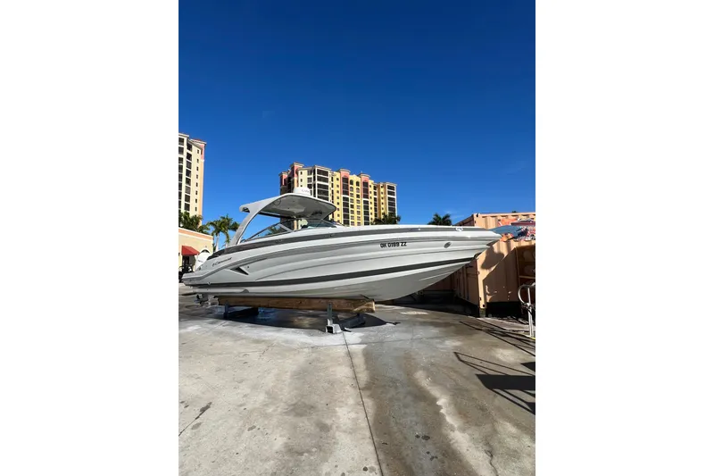 Slide: The Image of 2026 Crownline 310 XSS boat displayed outdoors with buildings in the background. - 2