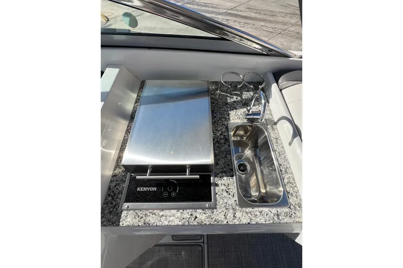 Slide: The Image of 2026 Crownline 310 XSS boat kitchenette with grill and sink on granite countertop. - 20