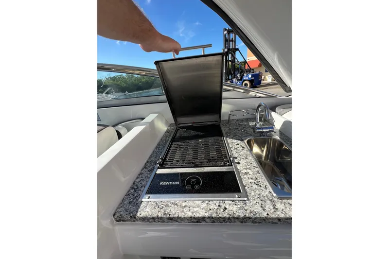 Slide: The Image of Crownline 310 XSS 2026 boat with Kenyon grill and sink on granite countertop. - 21