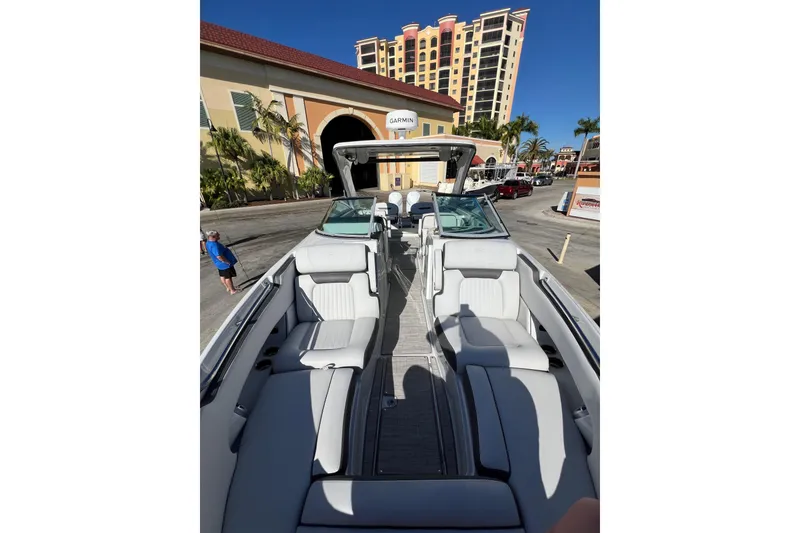 Slide: The Image of 2026 Crownline 310 XSS boat with luxurious seating, docked near a resort building. - 31