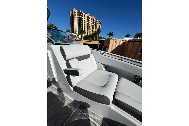 Slide: The Image of 2026 Crownline 310 XSS boat interior with white seating, urban backdrop. - 32