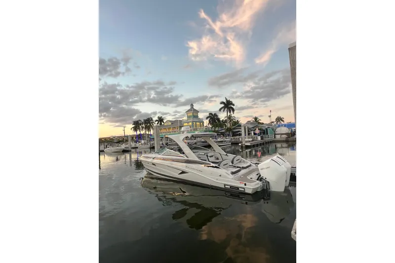 Slide: The Image of Crownline 310 XSS 2026 boat docked at sunset with palm trees and colorful sky. - 34
