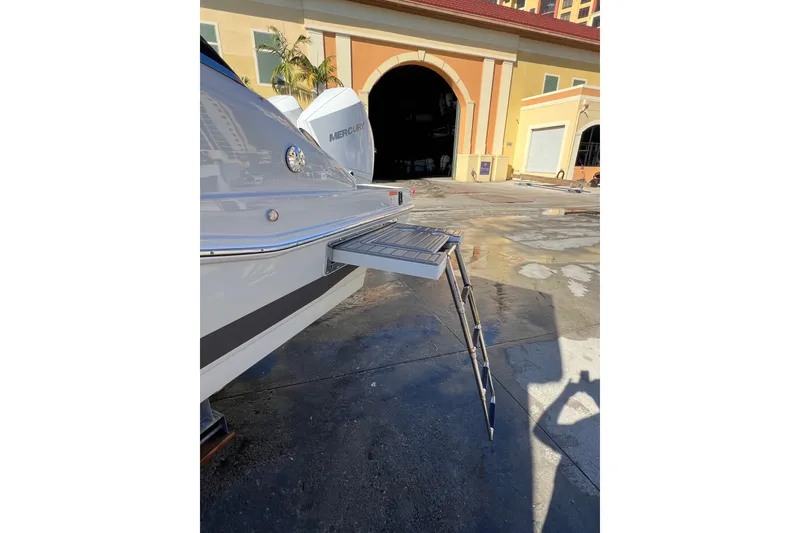 Slide: The Image of 2026 Crownline 310 XSS boat with extended swim platform and ladder in marina setting. - 8