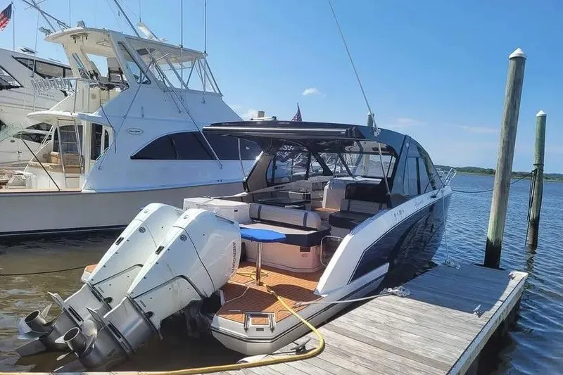 Slide: The Image of 2024 Hanover 387 boat docked, featuring dual outboard motors and spacious seating area. - 22