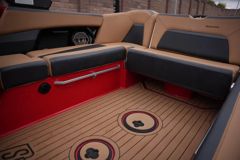 Slide: The Image of 2022 MasterCraft XStar S interior with tan and black seating, red accents, and teak-style flooring. - 14