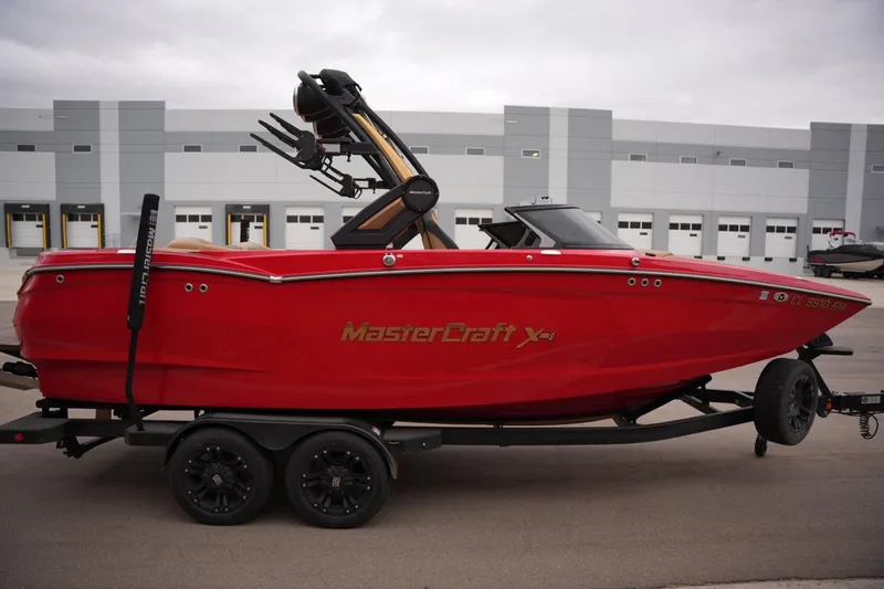 Slide: The Image of Red 2022 MasterCraft XStar S boat on trailer, parked in industrial area. - 5
